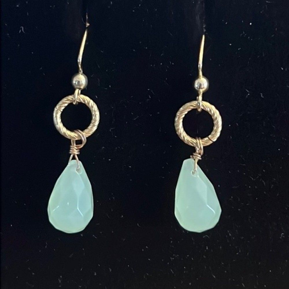 Handcrafted gold tone earrings with a green colored stone.